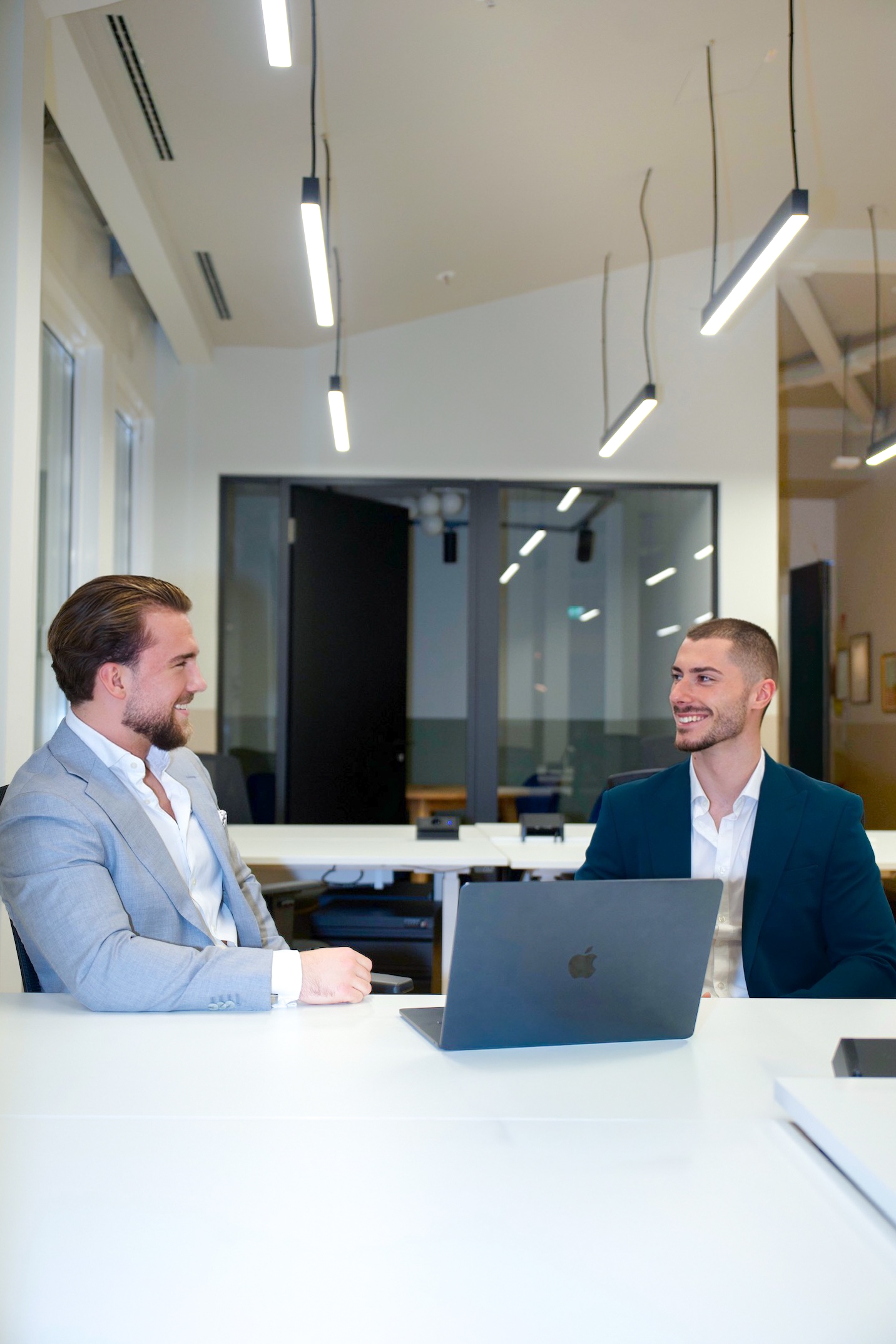 David und Niko lachen gemeinsam bei der Vorstellung eines neuen Dashboards